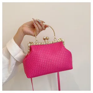 Dettaglio borsa da sera intrecciata rosa con telaio dorato vintage e chiusura a perla