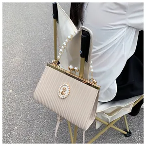Détail de l'ornement camée vintage et de l'anse en perles sur le sac à main crème