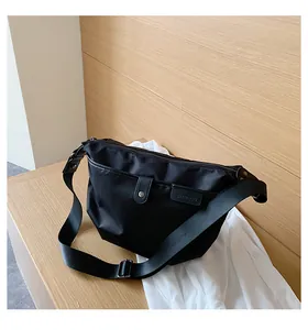 Detail of black waterproof nylon crossbody bag with metal snap and branded leather patch