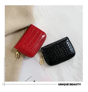 Détail de porte-cartes en similicuir rouge et noir avec texture crocodile et zip doré