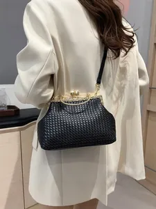 Elegante borsa a tracolla intrecciata nera con cornice dorata e chiusura a perla su blazer