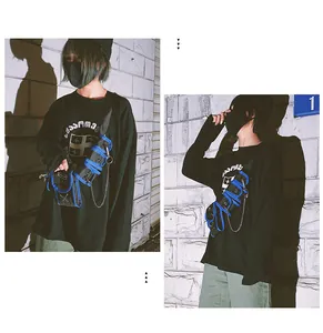 Detail shot of black streetwear crossbody bag with blue trim and metal chain on model