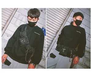 Detail of a black tactical chest rig with multiple pockets and industrial metal chain