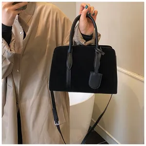 Detail van zwarte suède patchwork handtas met een verstelbare schouderriem