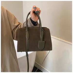 Detail van vintage bruine suède handtas met groene lederen bies en verstelbare schouderriem