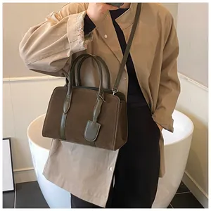 Detail van bruine suède shopper met groene leren handvaten en zilveren gespdetails