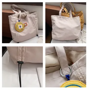 Detail of canvas tote bag with drawstring base and floral charm on wooden background