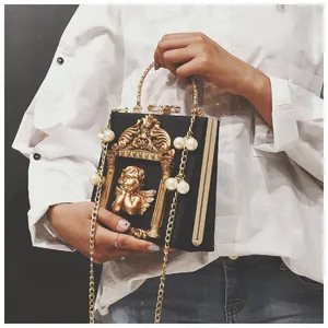 Detailed view of the vintage angel relief and pearl chain on the black leather handbag