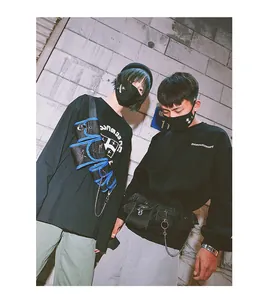 Close-up of tactical multi-pocket chest bag with metallic chains and streetwear hoodie
