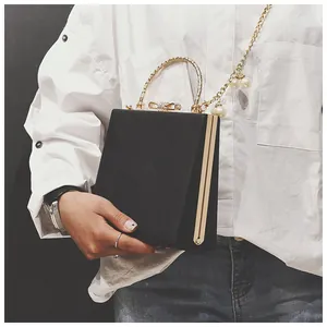 Close-up of black leather clutch bag with golden metal handle and pearl chain details