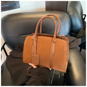 Gedetailleerde close-up van een vintage bruine suède tas met leren handvatten en metalen
