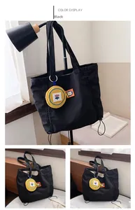 Detail of black canvas tote bag with a removable yellow flower charm and tulip embroidery
