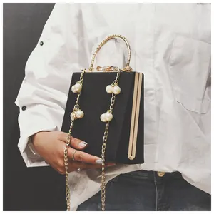 Detail of black box clutch with gold ring handle, rhinestone bow, and pearl chain strap