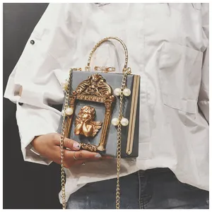 Detail of vintage square crossbody bag with gold angel relief and pearl chain strap