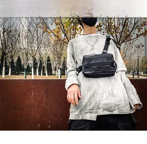 Outdoor street style view of a black nylon tactical crossbody bag with multiple zippers