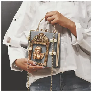 Detailed view of grey baroque box bag featuring gold angel relief and pearl chain strap