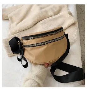 Detail of khaki crossbody bag featuring double metal zippers and fashion ribbon tag