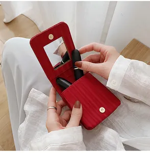 Red leather lipstick case with built-in mirror and magnetic closure held by hand
