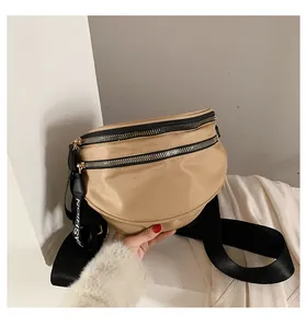 Detail of beige nylon crossbody bag featuring double black zippers and fashion strap