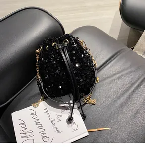 Close-up of black sequined bucket bag with gold chain strap and drawstring closure