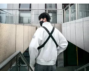 Détail du sac de poitrine tactique avec sangles croisées sur hoodie streetwear blanc
