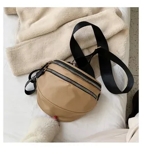 Detail of khaki crescent crossbody bag featuring dual zippers and fashion strap