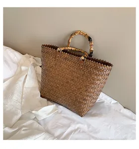 Detailed view of natural bamboo handles and textured woven fabric on a brown handbag