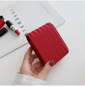 Close-up of a red vertical striped textured cosmetic bag held by hand for lipsticks