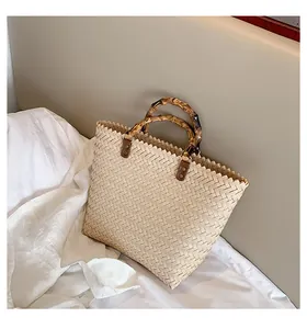 Close-up of woven tote bag with natural bamboo handles and serrated edge detail