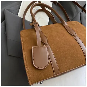 Detail van bruin suède en glad lederen stiksels op een tote bag met metalen noppen