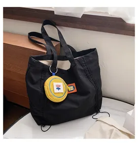 Close-up of black canvas tote bag with orange label and yellow floral embroidery pouch