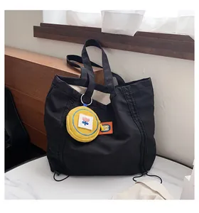 Detail of a black canvas tote bag with a small yellow floral coin purse attachment