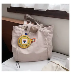 Detail of canvas tote bag featuring a yellow floral coin purse and drawstring accent