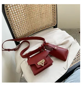 Detail of red leather belt bag set with golden triangle buckle and round pouch
