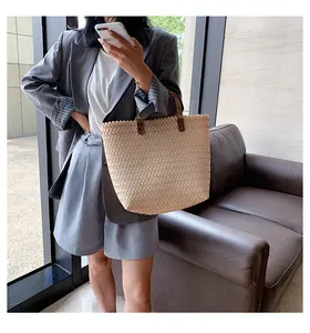 Detail of beige woven tote bag with herringbone texture and dark brown handles