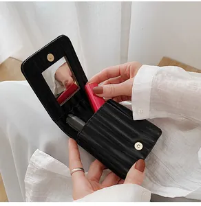 Close-up of black textured leather lipstick pouch with magnetic flap and built-in mirror