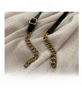 Close-up of vintage gold hardware chain and black leather strap with square buckle
