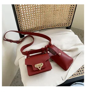 Detail of a dark red leather belt bag set with a golden triangle buckle on a chair
