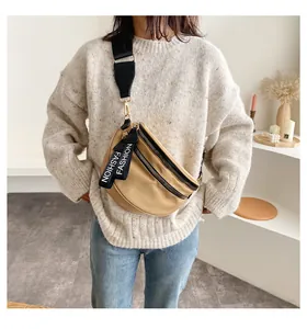 Khaki crossbody fanny pack with dual zippers shown on model wearing white sweater