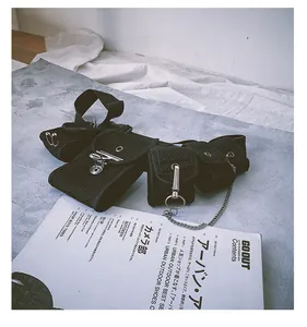 Detailed view of black tactical bag with metal chains on a textured stone surface