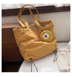 Detail of yellow canvas tote bag with drawstring texture and small flower purse charm