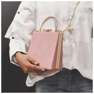 Pink suede square handbag featuring a gold butterfly clasp and pearl chain strap details