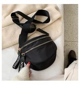 Detail of black nylon crescent crossbody bag with gold zippers and fashion webbing strap