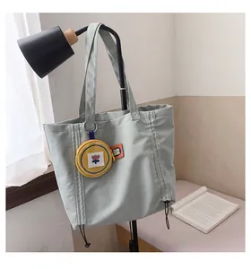 Detailed view of canvas tote bag with pleated design and yellow flower coin purse charm