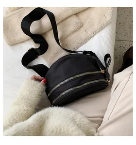 Detail of black crossbody chest bag with double gold zippers and FASHION logo strap