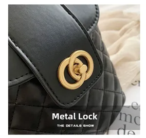 Macro shot of the elegant golden interlocking hardware lock on a black quilted bucket bag