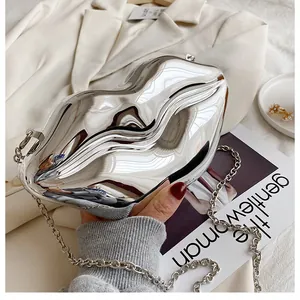 Polished silver lip-shaped clutch bag with metal chain strap on fashion magazine