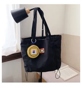 Detail of black canvas tote bag with drawstring side and yellow flower coin purse charm