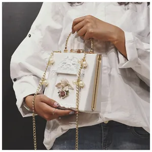 Detail of vintage white box bag featuring angel relief and rose with pearl chain strap