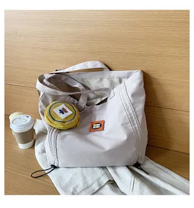 Detail of beige canvas tote bag with orange label and yellow floral coin purse